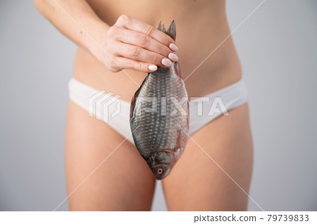 Woman's intimate hygiene and health concept. A faceless girl in white panties is holding a fish 79739833