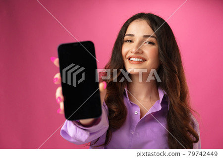 Attractive young woman showing blank smartphone screen with copy space Attractive young woman showing blank smartphone screen with copy space 79742449