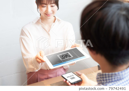 Female staff reading the QR code displayed on the smartphone with a tablet 79742491