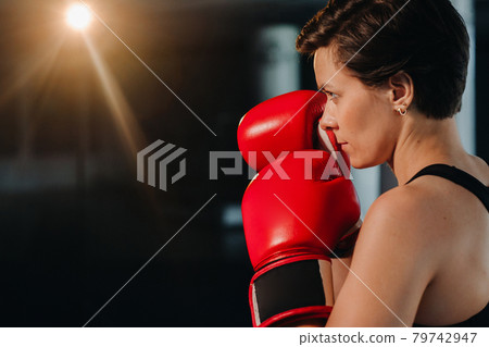 portrait of a female boxer in red gloves in the gym during training 79742947