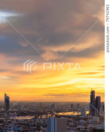 Aerial view of Bangkok city Overlooking Skyscrapers and the Bridge crosses the Chao Phraya river with bright glowing lights at dusk. Aerial view of Bangkok city Overlooking Skyscrapers and the Bridge crosses the Chao Phraya river with bright glowing lights at dusk. 79742962