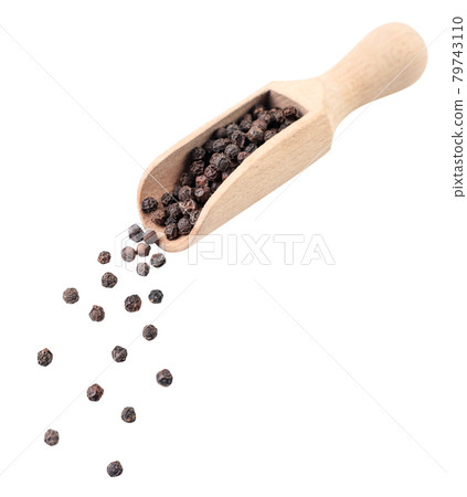 Black peppercorns spilling out from a wooden scoop on a white background. Isolated 79743110