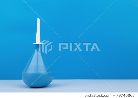 Blue medical enema on white table against blue background with copy space Blue medical enema on white table against blue background with copy space 79746863