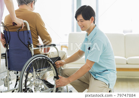 Caregiver checking wheelchair brakes 79747884