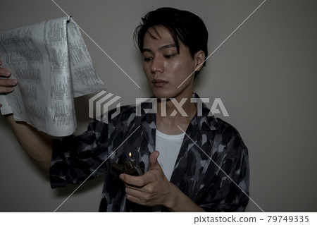 A man burning a newspaper 79749335