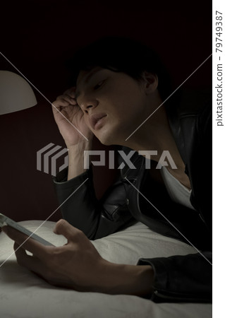 Men watching smartphones in bed Men watching smartphones in bed 79749387
