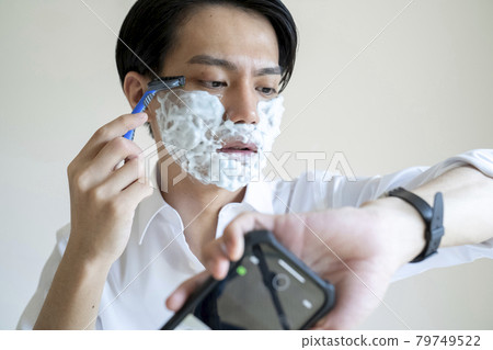 A man shaving his beard A man shaving his beard 79749522