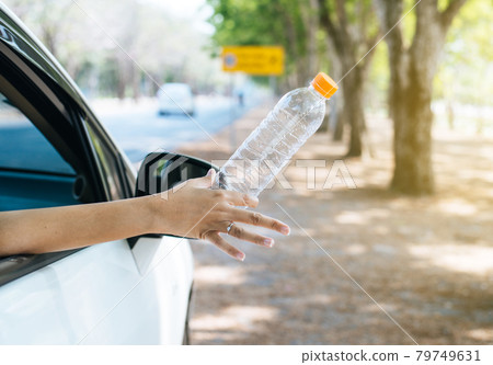 Woman hand throwing plastic bottle trash on the road,Environment and pollution campaign concept Woman hand throwing plastic bottle trash on the road,Environment and pollution campaign concept 79749631
