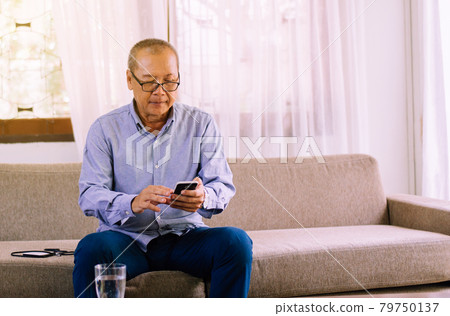 Senior asian man wearing glasses and using mobile phone at home,Relax time,Senior lifestyle concept,Long sighted Senior asian man wearing glasses and using mobile phone at home,Relax time,Senior lifestyle concept,Long sighted 79750137