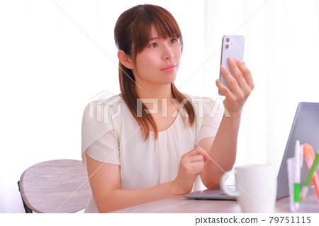 A woman looking at her smartphone with a dissatisfied look 79751115