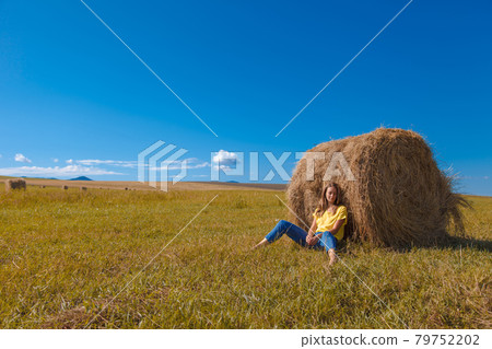 a girl is sunbathing in the hay. village life: harvesting hay for the winter. animal feed. 79752202
