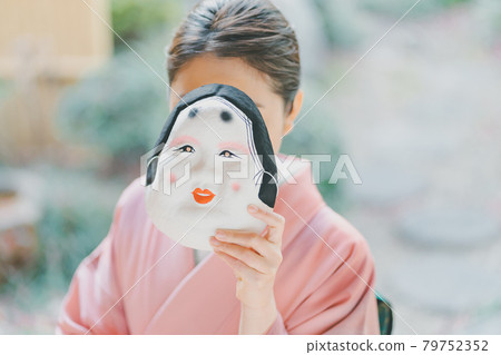 A woman in her twenties wearing a okame mask and a kimono A woman in her twenties wearing a okame mask and a kimono 79752352