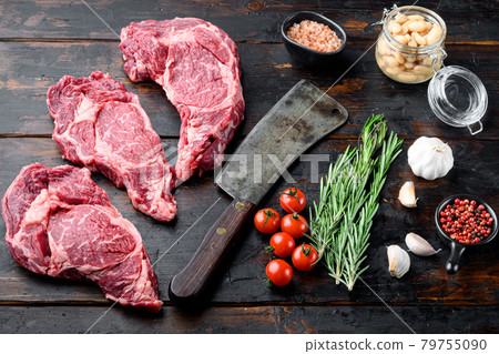 Raw fresh meat Ribeye steak entrecote of Black Angus Prime meat with ingredients, and old butcher cleaver knife, on old dark wooden table background Raw fresh meat Ribeye steak entrecote of Black Angus Prime meat with ingredients, and old butcher cleaver knife, on old dark wooden table background 79755090