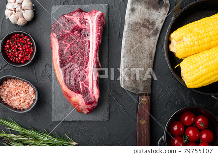 Raw beef meat Club or striploin on the bone steak with ingredients, on black stone background, top view flat lay Raw beef meat Club or striploin on the bone steak with ingredients, on black stone background, top view flat lay 79755107