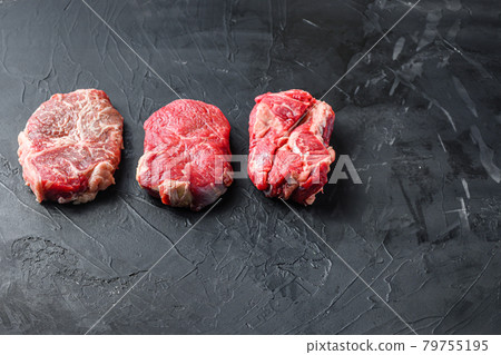 Set of raw alternative cuts beef steaks, top blade, rump and chuck roll, on black textured background, side view with space for text. Set of raw alternative cuts beef steaks, top blade, rump and chuck roll, on black textured background, side view with space for text. 79755195