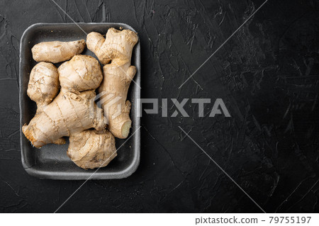 Fresh ginger root or rhizome, in plastic market container, on black stone background, top view flat lay, with copy space for text Fresh ginger root or rhizome, in plastic market container, on black stone background, top view flat lay, with copy space for text 79755197