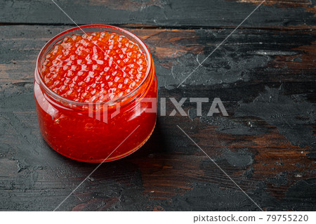 Glass jar with delicious red caviar, on old dark wooden table background with copy space for text 79755220