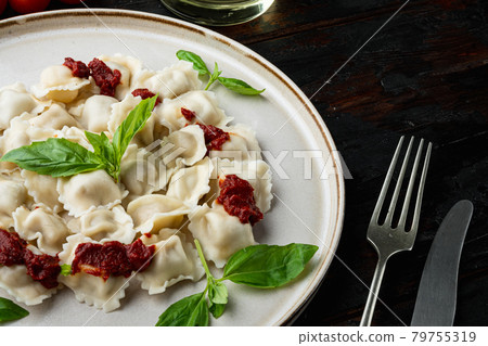 Ravioli pasta with mushroom cream sauce and cheese - Italian food style with basil parmesan and tomatoe on white plate on old dark wooden table background 79755319