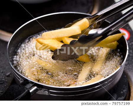 Close up of Frying french fries in the fryer in hot oil on the electric stove in the kitchen. Making homemade french fries. 79757199