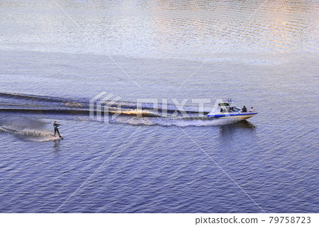 Foam waves behind a boat with a water skier on the river at sunset, July 2021 79758723