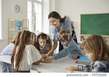 Happy school teacher and little kids reading books and learning new things together Happy school teacher and little kids reading books and learning new things together 79758899