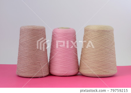 Pastel color bobbins of wool yarn for hand and machine knitting on a pink background Pastel color bobbins of wool yarn for hand and machine knitting on a pink background 79759215