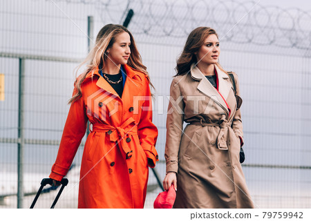 Two happy girls walking near airport, with luggage. Air travel, summer holiday Two happy girls walking near airport, with luggage. Air travel, summer holiday 79759942