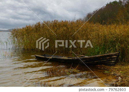 An old boat on the shore of the lake in the autumn on a cloudy day. An old boat on the shore of the lake in the autumn on a cloudy day. 79762603