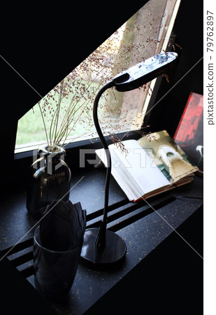 Lamp, books, glass with napkins and a vase still life view near cafe window 79762897