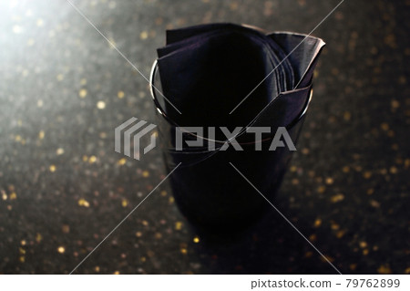 Black tissues in black glass on dark cafe table with golden dust glitter surface Black tissues in black glass on dark cafe table with golden dust glitter surface 79762899