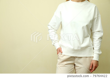 Young woman in white sweatshirt against beige background Young woman in white sweatshirt against beige background 79764422