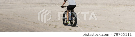 Man riding a fat wheel bike on the beach 79765111