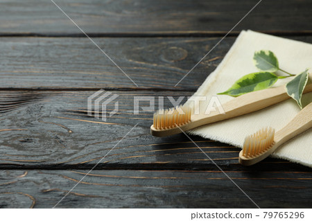 Napkin with eco friendly toothbrushes and twig on wooden background Napkin with eco friendly toothbrushes and twig on wooden background 79765296