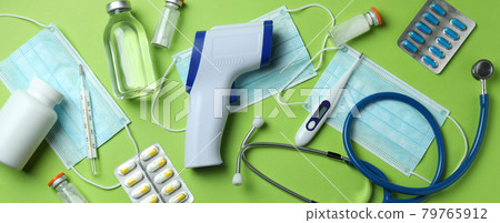 Medical tools and thermometer gun on green background 79765912