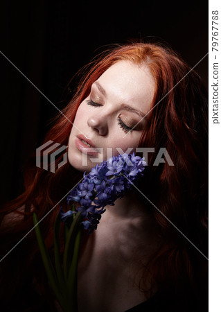 Portrait of girl with long red hair, good skin, with hyacinth on a black background 79767788
