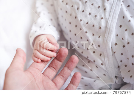 Mothers hand hold baby hand. One month old. Concept of love and care Mothers hand hold baby hand. One month old. Concept of love and care 79767874