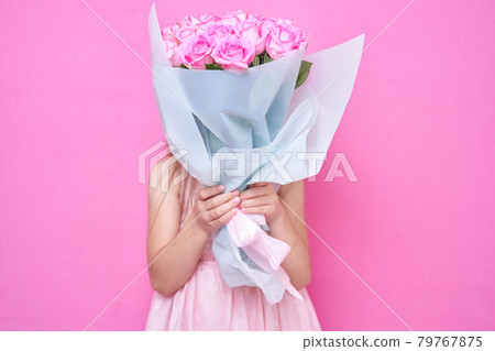A girl in pink dress with bouquet of roses, hid behind the flowers. A girl in pink dress with bouquet of roses, hid behind the flowers. 79767875