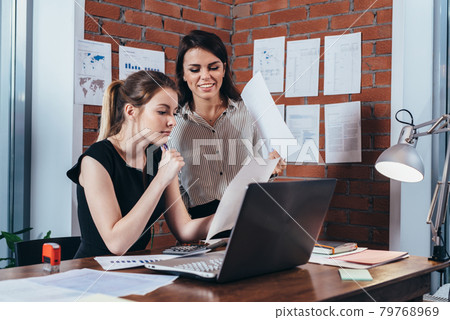 Two female colleagues in office working together. Two female colleagues in office working together. 79768969