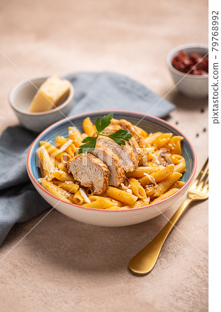Pasta penne with cajun sauce and fried chicken on a table 79768992