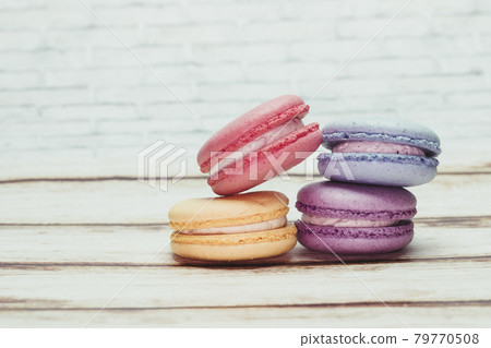 Multicolored macarons on a table and white wall background 79770508