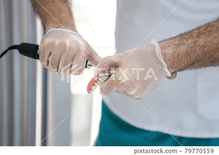 The dentist corrects the denture 79770559