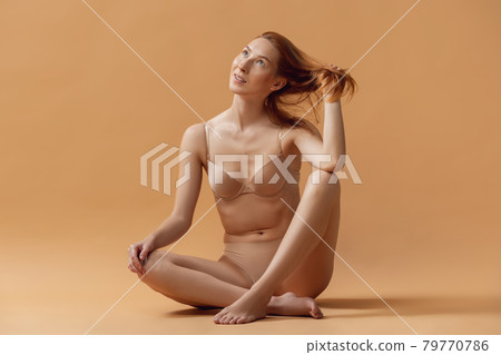 Young beautiful woman in lingerie posing isolated over sand color studio back ground. The fitness, diet, sports, natural beauty and aesthetic cosmetology concept. 79770786