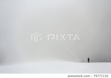 Far away lonely figure of a man standing outdoors in winter 79771130