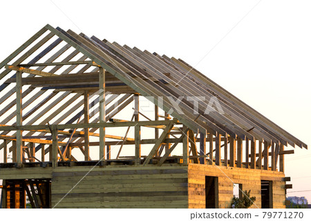 Close-up detail of new attic wooden roof frame against clear sky. Professional building, roofing, construction and renovation concept. Investment in real estate property and ecological home concept. Close-up detail of new attic wooden roof frame against clear sky. Professional building, roofing, construction and renovation concept. Investment in real estate property and ecological home concept. 79771270