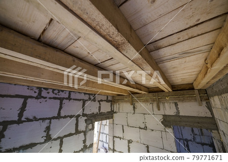 Close-up detail of house room interior under construction and renovation. Energy saving walls of hollow foam insulation blocks, wooden ceiling beams for roof frame. 79771671