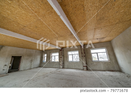 Unfinished apartment or house big loft room under reconstruction. Plywood ceiling, plastered walls, window openings, cement floor. Construction and renovation concept. Unfinished apartment or house big loft room under reconstruction. Plywood ceiling, plastered walls, window openings, cement floor. Construction and renovation concept. 79771678