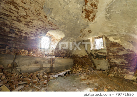 Old forsaken empty basement room of ancient building or palace with cracked plastered brick walls, low arched ceiling, small windows with iron bars and dirty floor. Old forsaken empty basement room of ancient building or palace with cracked plastered brick walls, low arched ceiling, small windows with iron bars and dirty floor. 79771680
