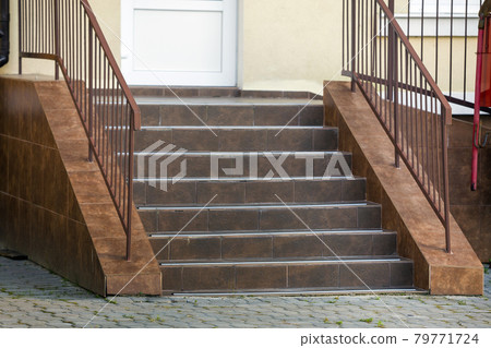 Concrete stairs covered with ceramic tiles with metal railings outdoors. 79771724