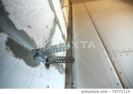 Unfinished brick wall in a room under construction prepared for drywall plates frame installation. Unfinished brick wall in a room under construction prepared for drywall plates frame installation. 79772114