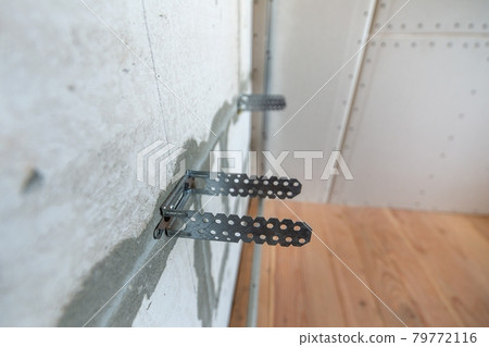 Unfinished brick wall in a room under construction prepared for drywall plates frame installation. Unfinished brick wall in a room under construction prepared for drywall plates frame installation. 79772116